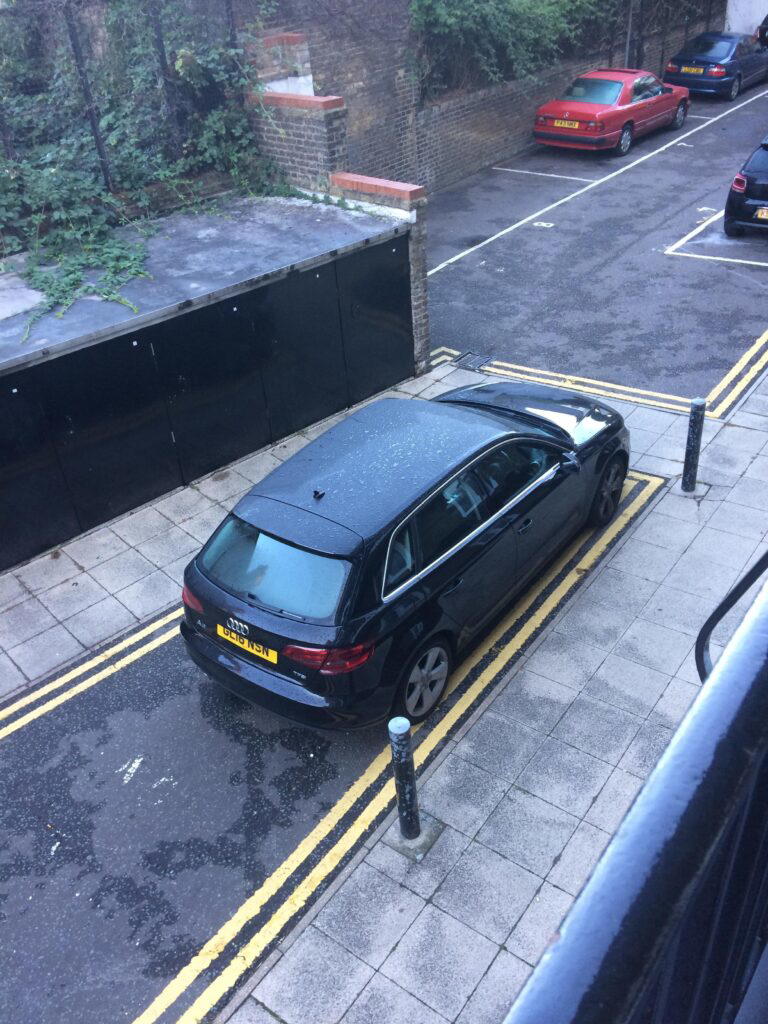 A car parked on double yellow lines at the end of a narrow lane